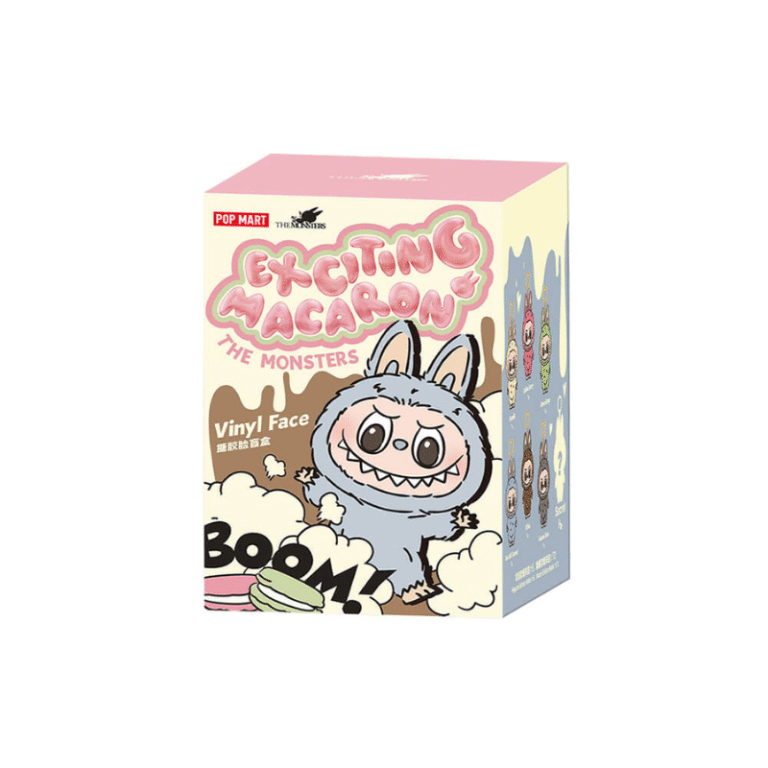 a close-up of the Exciting Macaron blind box packaging. The box features a colorful design with a character from The Monsters series, dressed in a bunny outfit. The playful design includes fun elements like macarons, clouds, and the word "BOOM!" The box also features the text Vinyl Face, indicating that the item inside is a vinyl figure, part of a collectible series. The overall aesthetic is vibrant and whimsical, capturing the essence of the collectible's fun and adorable style