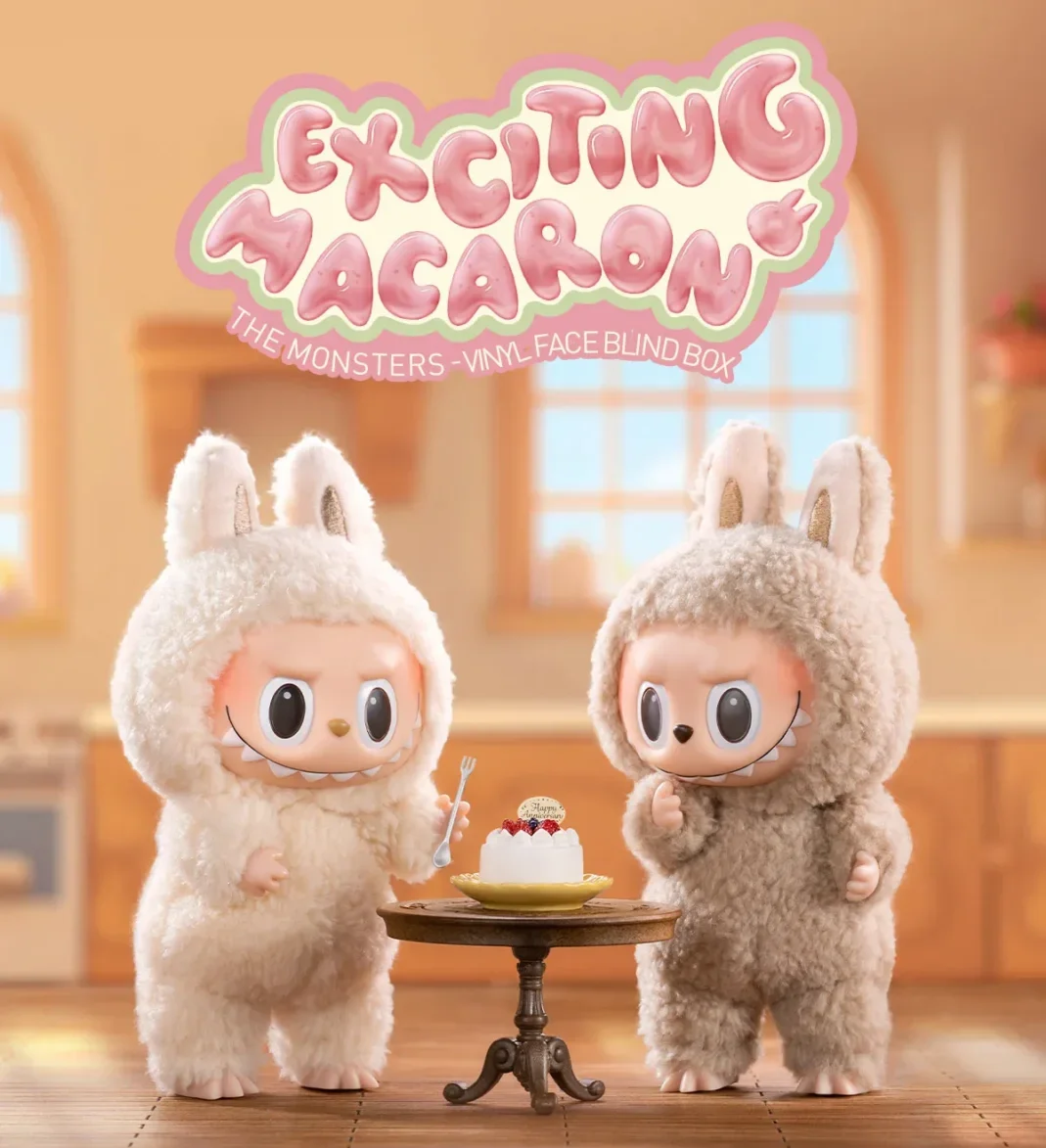 Two Labubu plush toys in fluffy bunny costumes are sitting at a table with a cake in a kitchen setting. One plush is holding a fork and about to eat while the other is playfully looking at the cake. The 'Exciting Macaron' logo is featured at the top, with the 'Vinyl Face Blind Box' subtitle